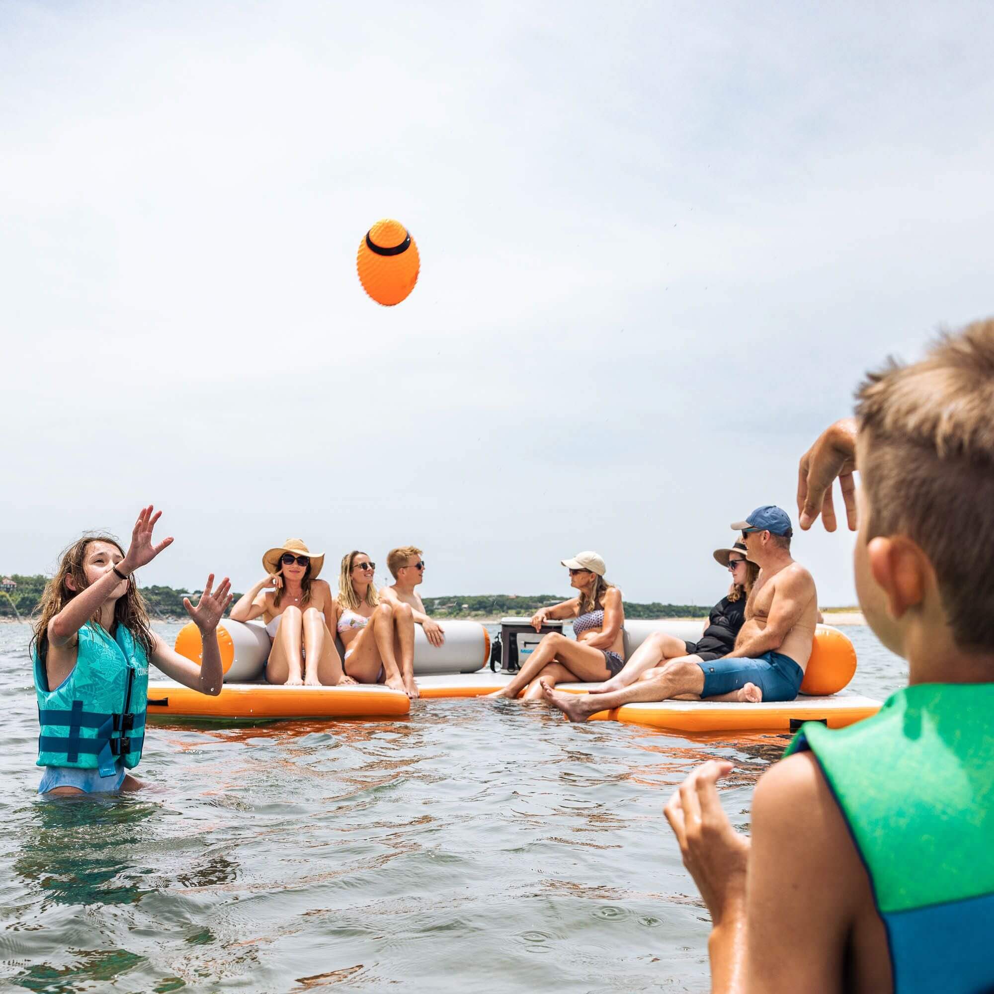 A group of people on MISSION inflatable mats playing a game of frisbee.