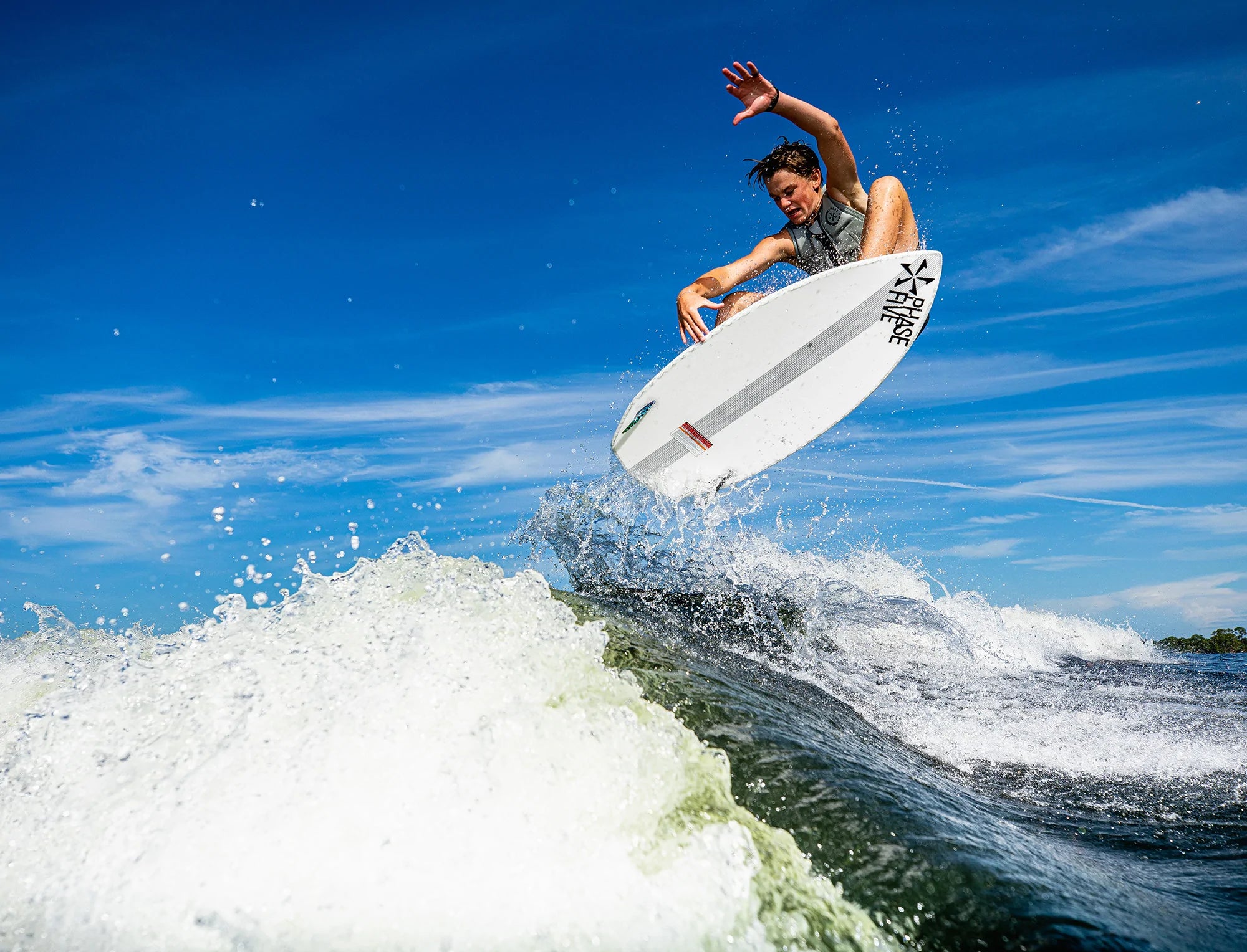 A man is riding a wave on a Phase 5 2023 Aku V2 Wakesurf Board with incredible speed.