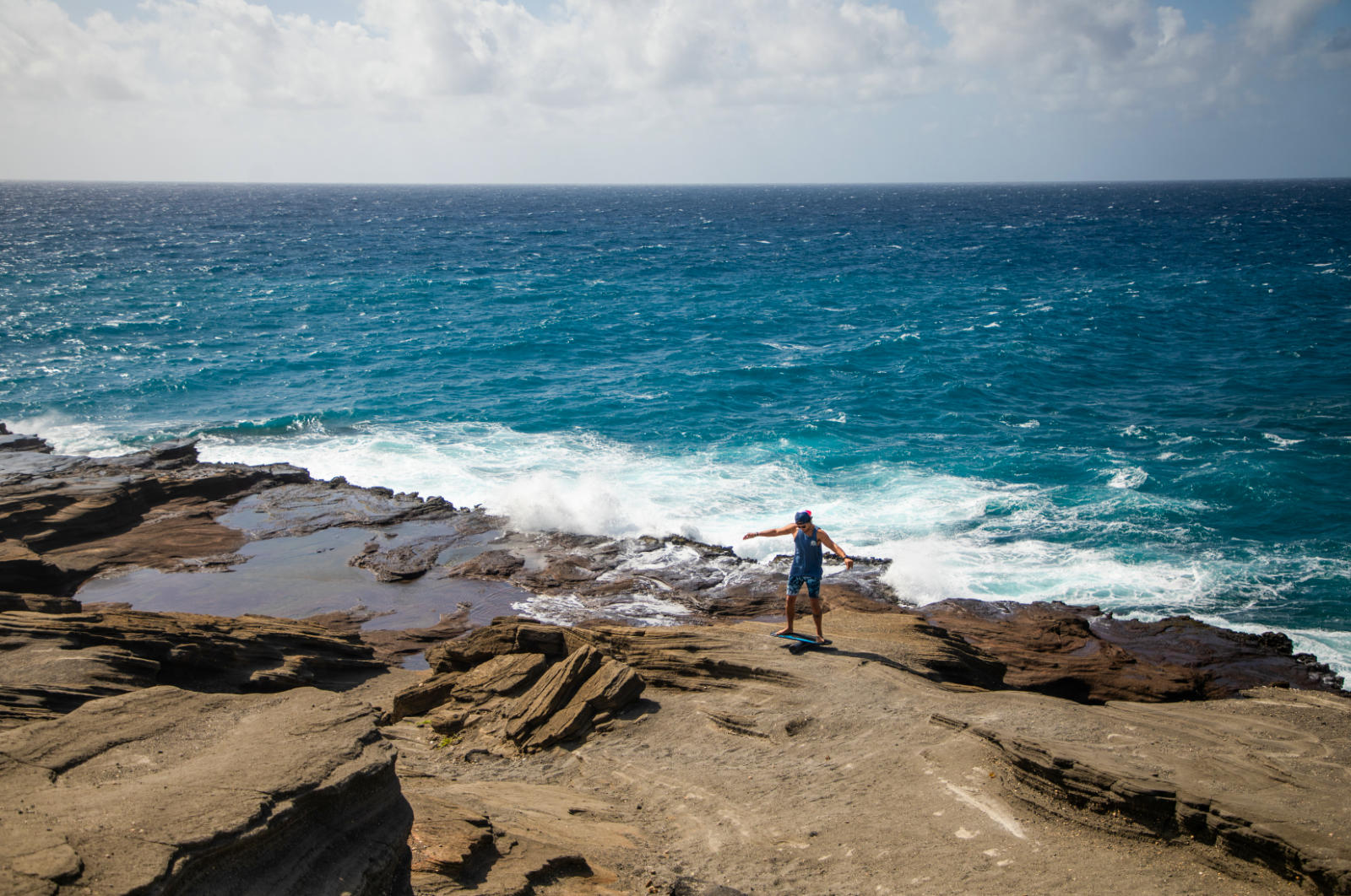 A person using a Revolution Swell 2.0 Balance Board on a rocky cliff overlooking the ocean.