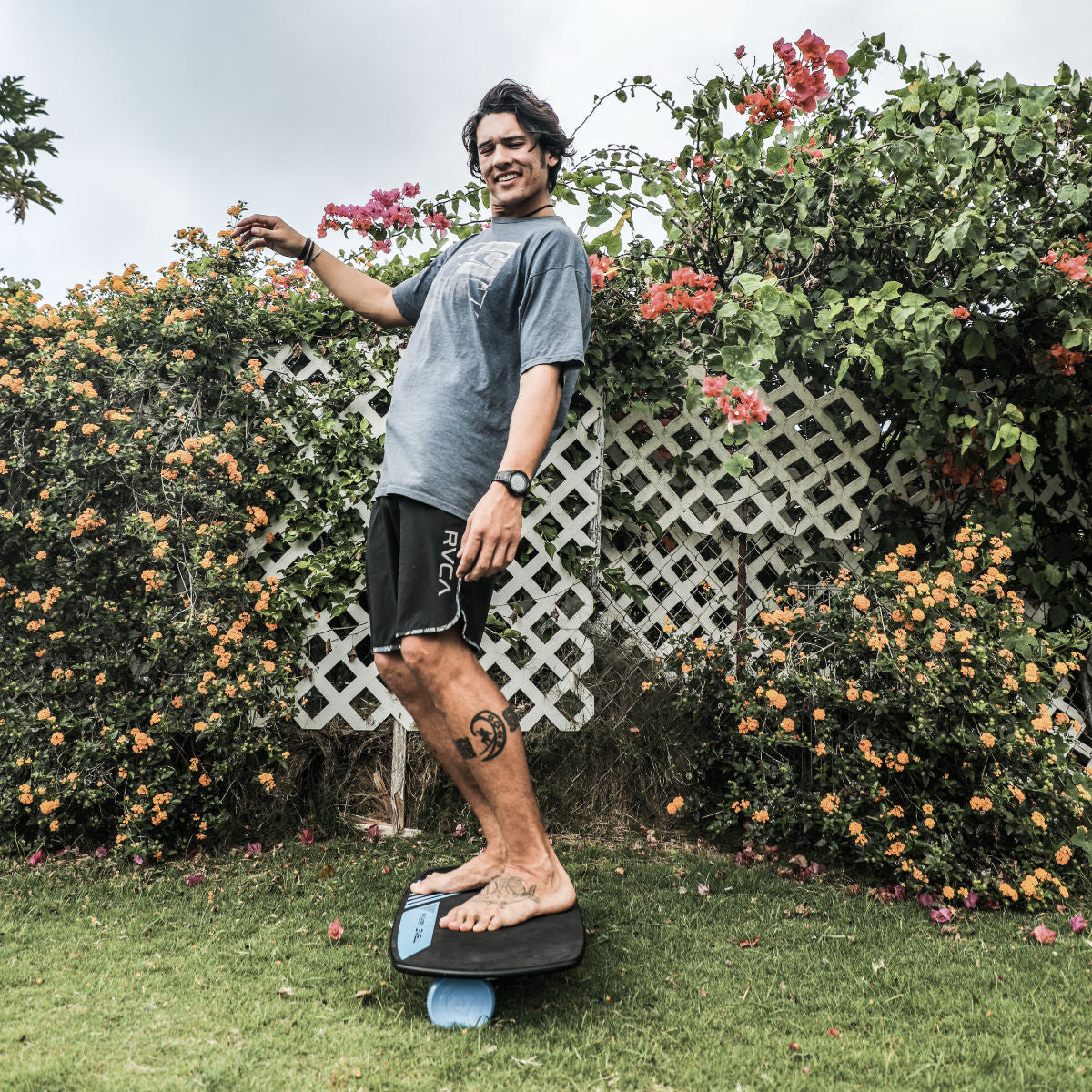 A man balancing on a Revolution Swell 2.0 Balance Board in a garden.