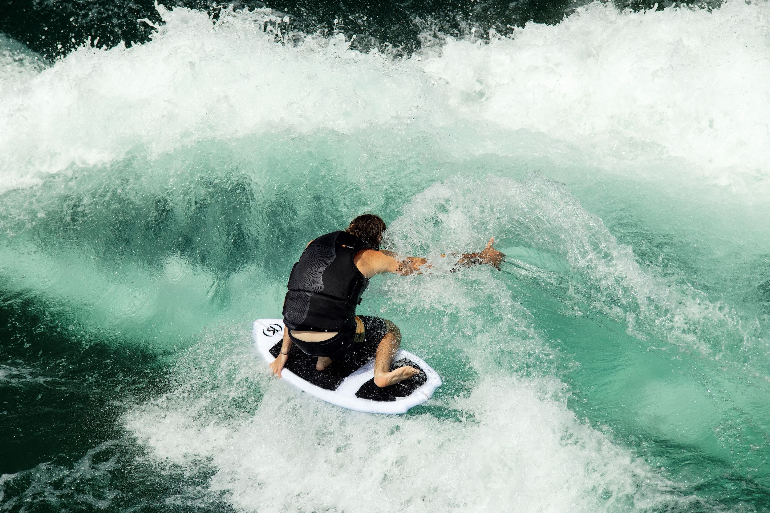 A surfer showcasing exceptional performance on a Ronix 2024 Flyweight Atlantik Wakesurf Board as he rides a wave.