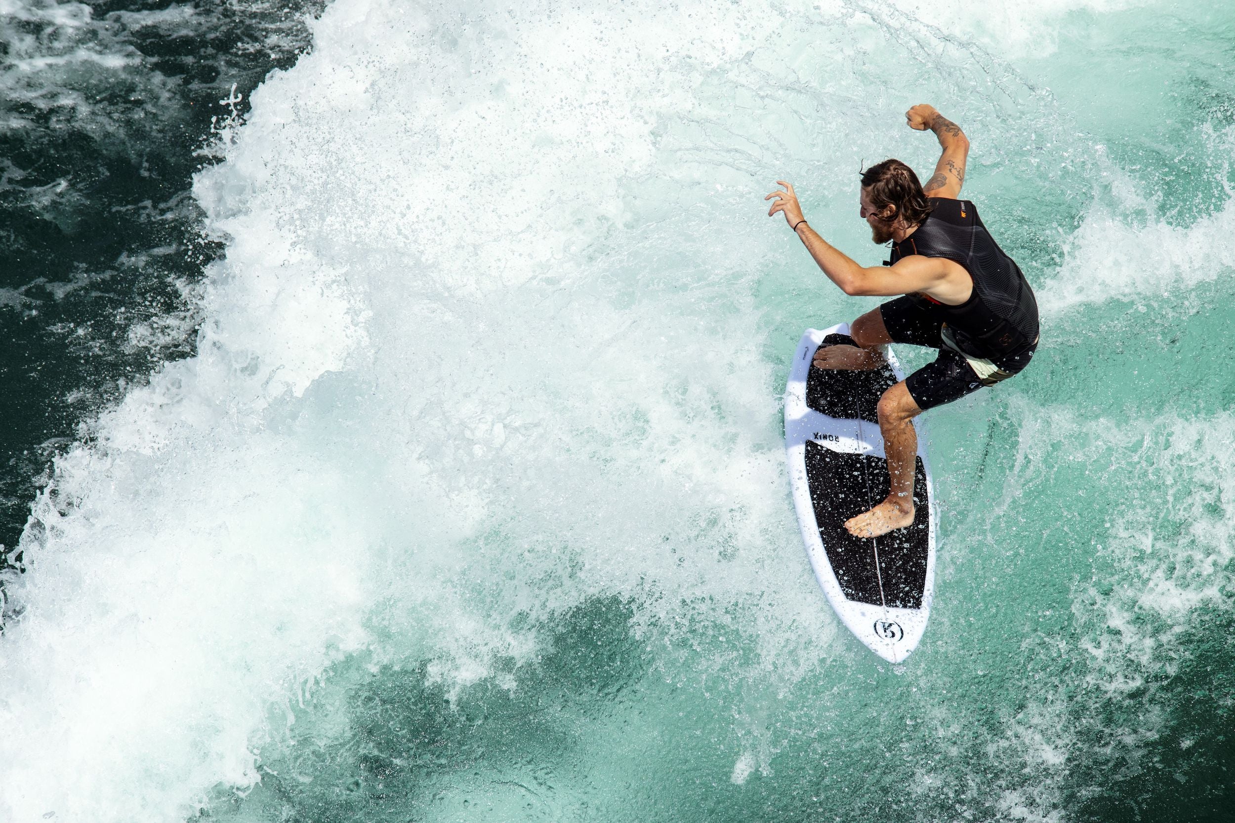 A surfer showcasing a remarkable performance on a Ronix 2024 Flyweight Atlantik Wakesurf Board as he rides a wave.