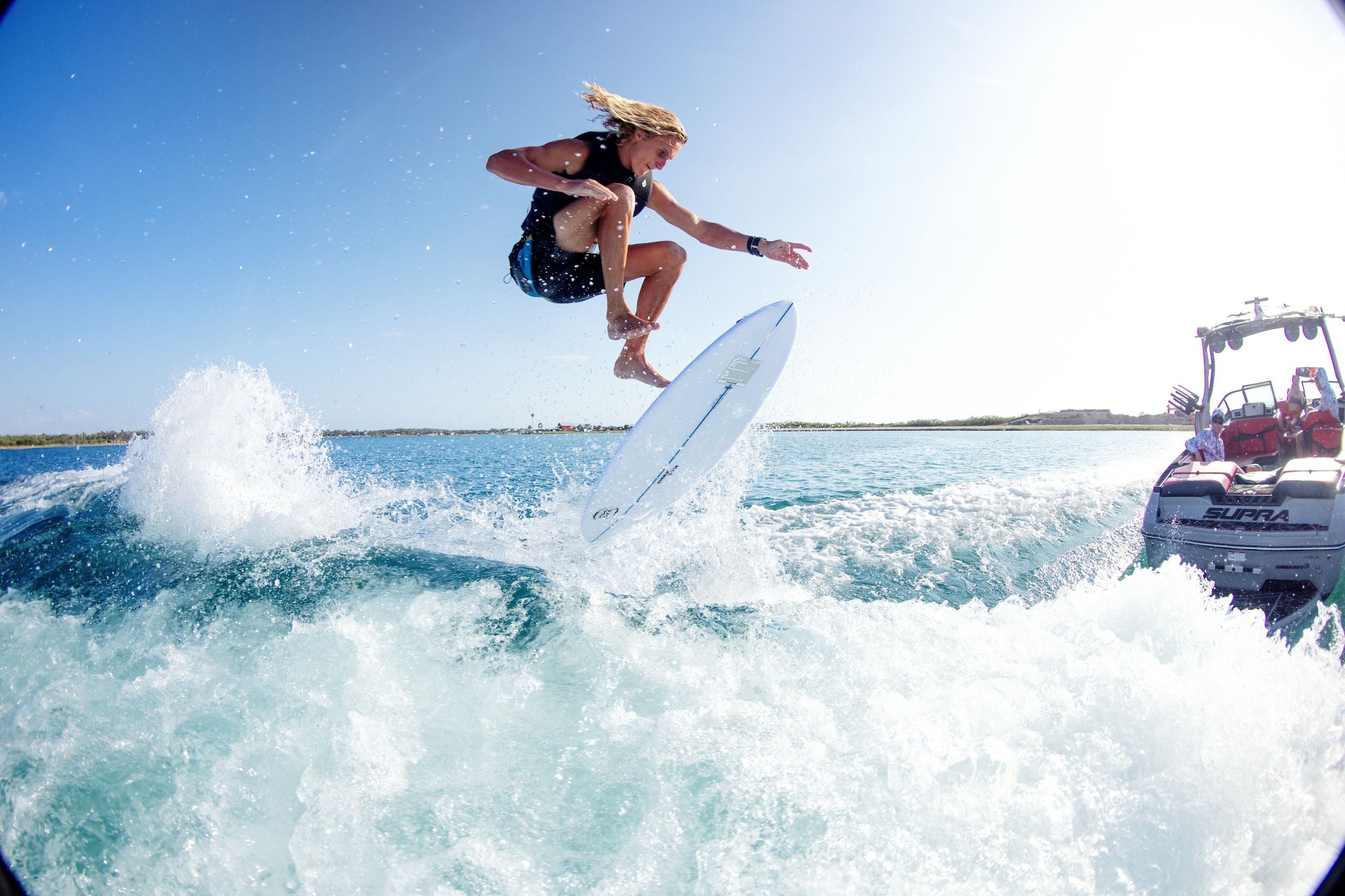 A man is performing a trick marvel on a Ronix 2024 Flyweight Skimmer surfboard, showcasing his board control in the water.