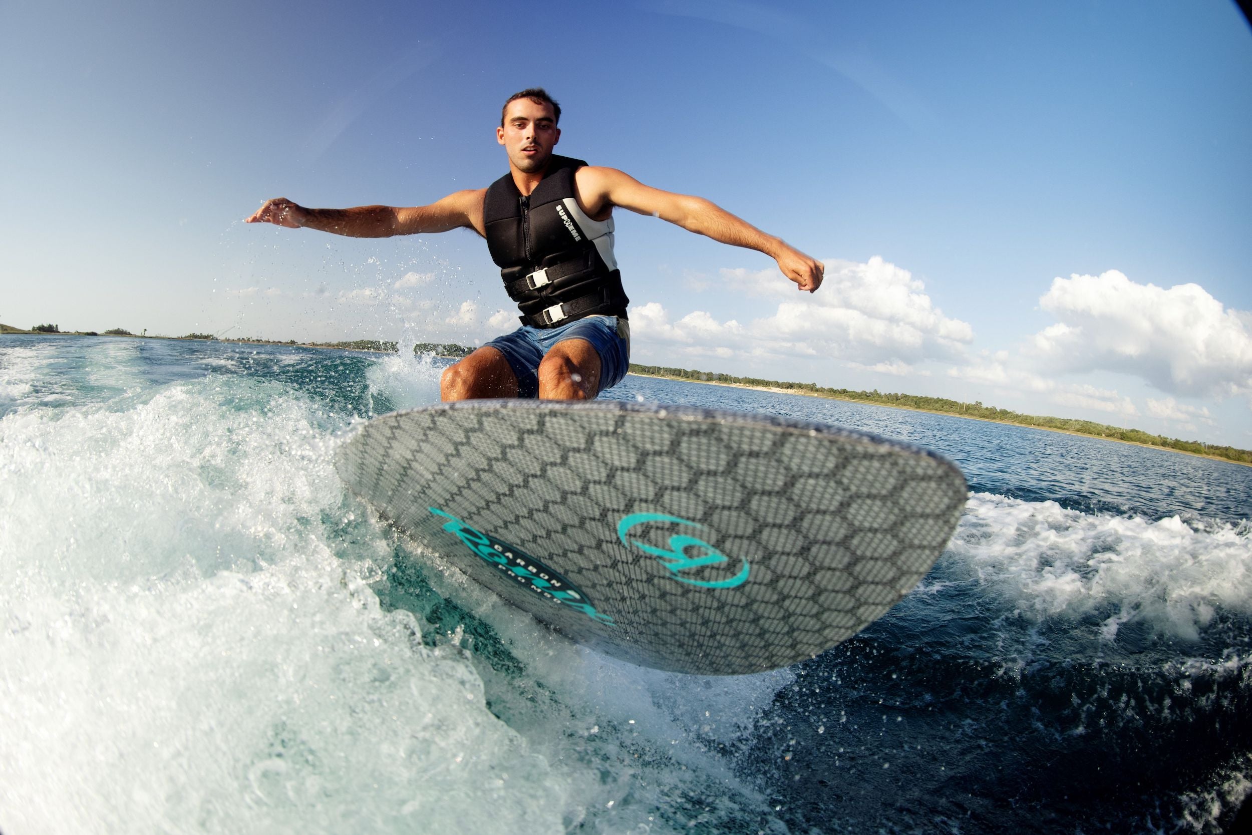 A man riding a wave on a surfboard, showcasing his supreme buoyancy and mobility with the Ronix 2024 Supreme Yes Men's CGA Vest.
