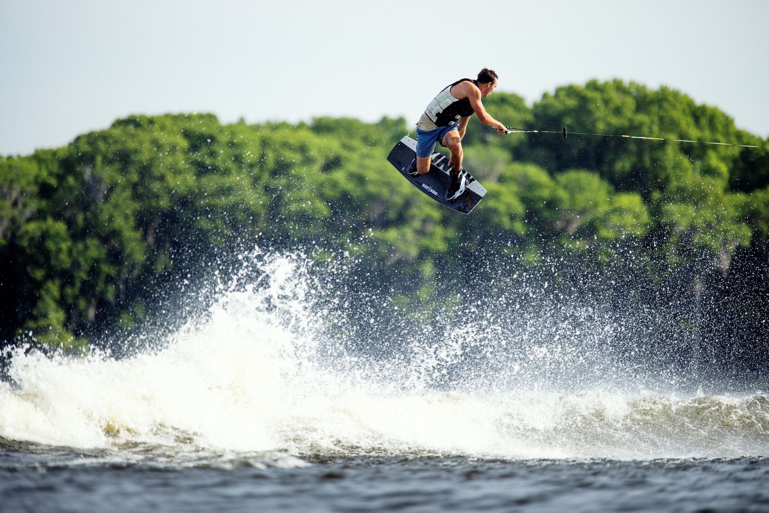 A man in a Manhattan Tailored Fit wakeboarding with buoyancy and mobility, wearing a Ronix 2024 Supreme Yes Men's CGA Vest.