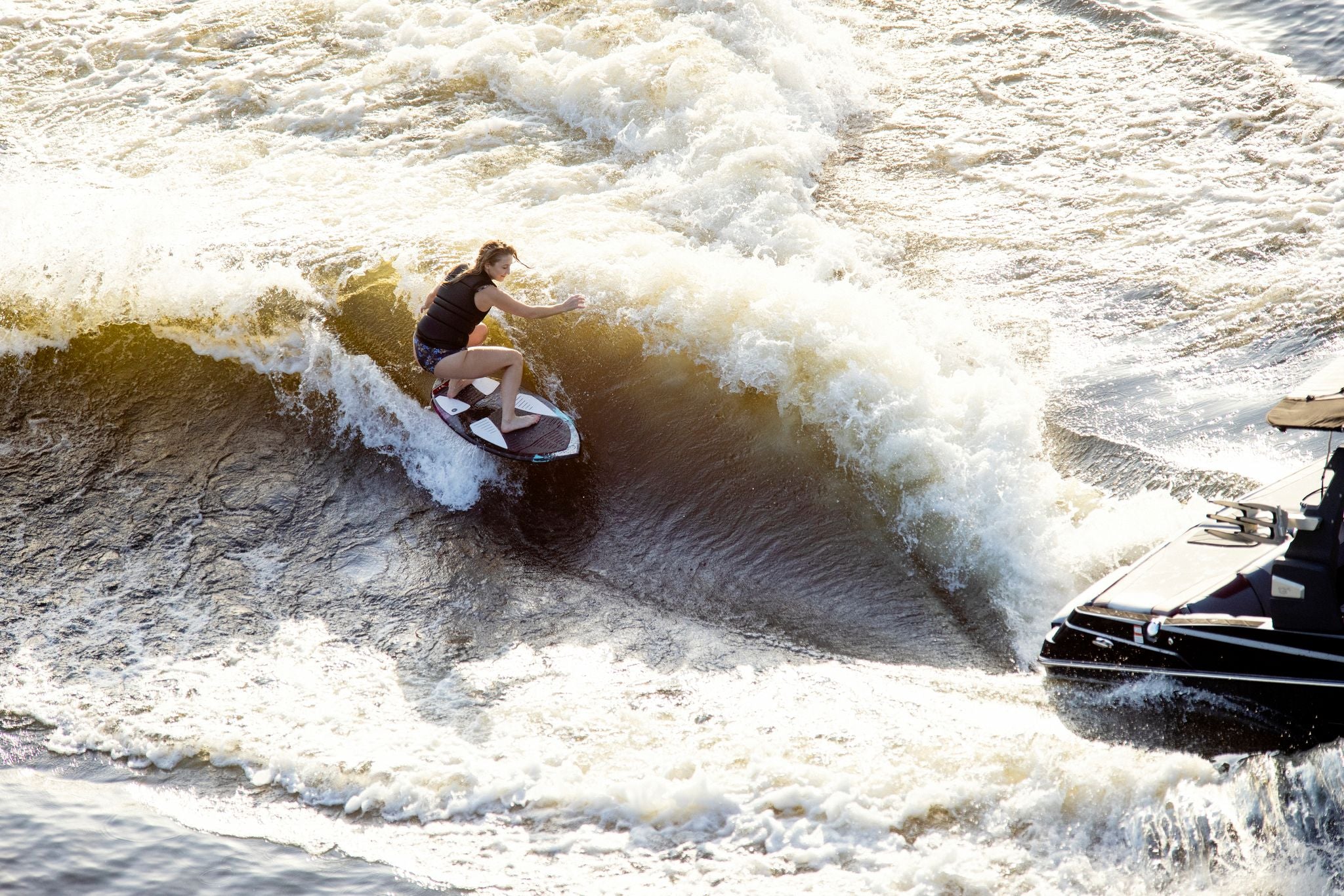 A man is riding a wave on a Ronix 2024 Women's Carbon Air Core 3 Skimmer Wakesurf Board for enhanced performance.