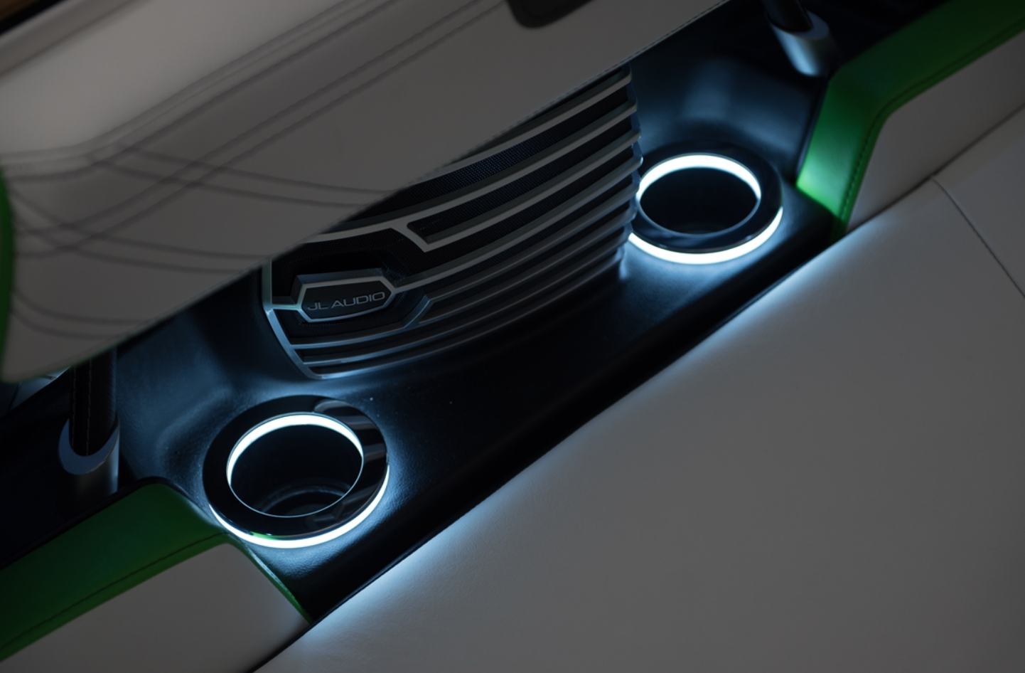 Close-up of a Nautique LED Cup Holder- White (160384) by Nautique with blue lighting and a JL Audio speaker in a white and green boat interior, highlighting sleek boating accessories.