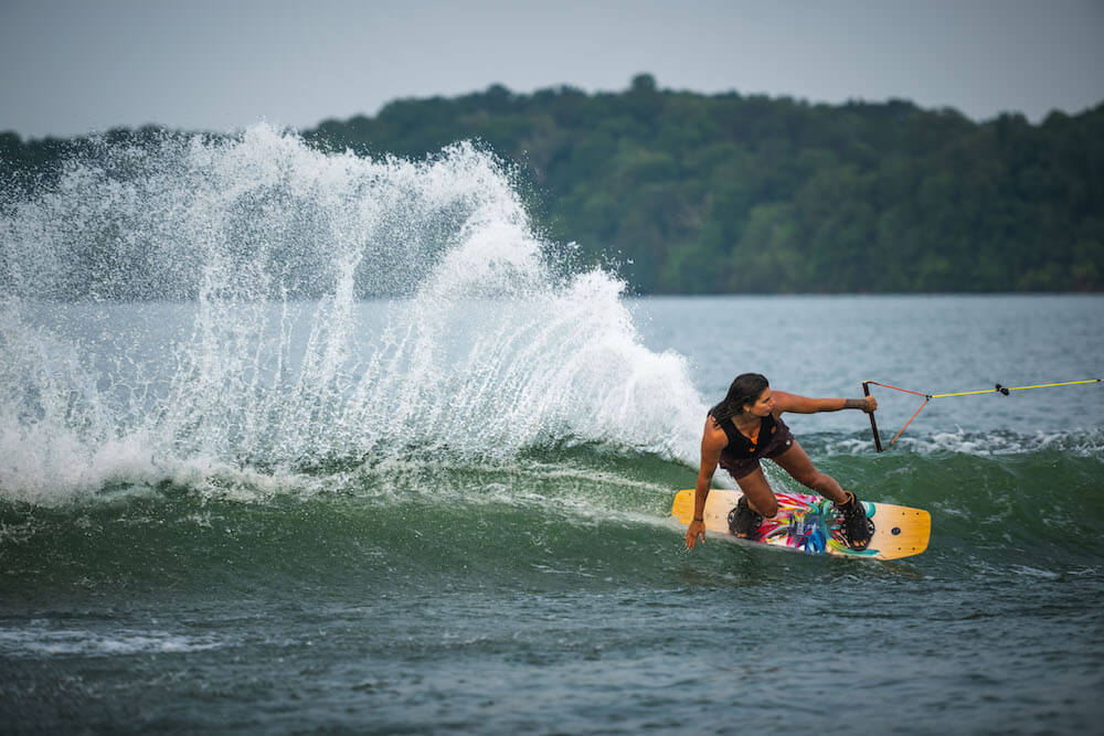 A person riding a Hyperlite 2024 Prizm Wakeboard on a lake, showcasing the amazing performance of the Satin Flex and Prizm technologies.