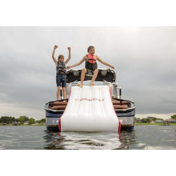 Two boys are jumping on top of a Connelly Boat Slide.
