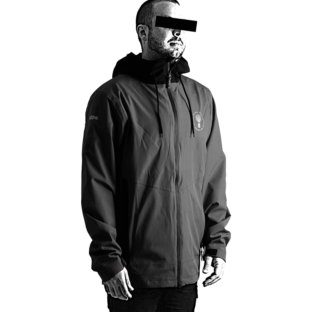 A man wearing a Follow Wake 2021 Follow Layer 3.1 Outer Spray Twelker - Charcoal jacket standing in front of a black background.