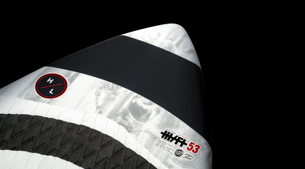 Close-up of the Hyperlite 2025 Hi-Fi Wakesurf Board showcasing black, white, and gray stripes against a black background. The board highlights its DuraShell construction for enhanced durability and features an EVA Traction pad for exceptional grip.