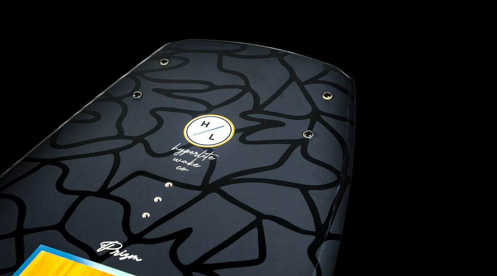 Close-up of the Hyperlite 2025 Prizm Wakeboard, showcasing a geometric pattern and the Hyperlite logo on a black background. It is crafted with Biolite 3 Core for durability and enhanced by a subtle 3-Stage Rocker design.