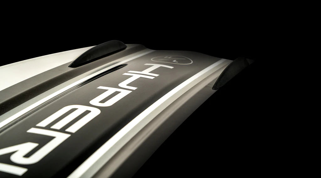 Close-up of a black and white object with the word HYPER written on it, reminiscent of the sleek design of a Hyperlite 2025 Rusty Pro Wakeboard against a dark background.