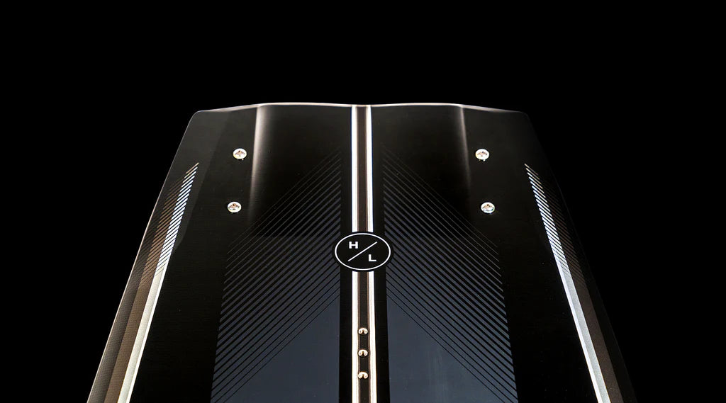 Close-up view of the Hyperlite 2025 Rusty Pro Wakeboard, featuring a sleek black design with silver accents and a circular logo at its center, against a black background.