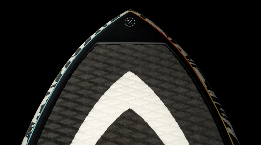 Close-up of the Hyperlite 2025 Shim Wakesurf Board tip against a black background, highlighting a textured black and white geometric pattern with DuraShell Construction for improved durability.