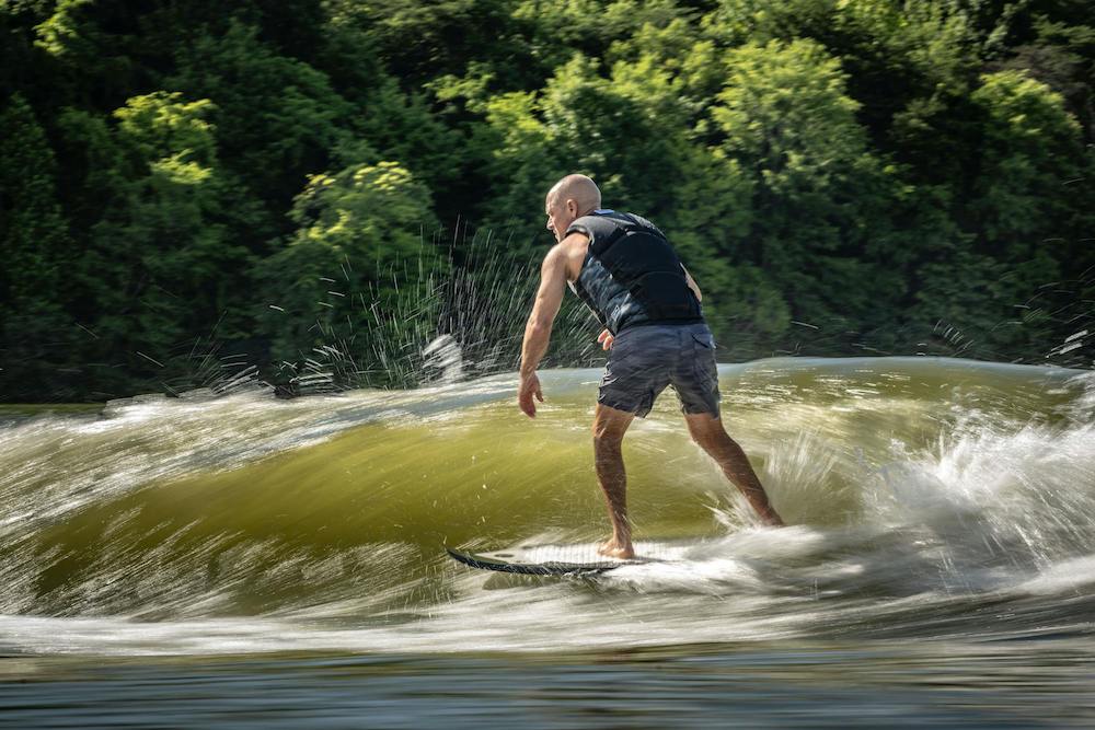 Hyperlite 2025 Broadcast is ridden by Shaun Murray as he leans forward on the board to stay in the pocket of the wave.