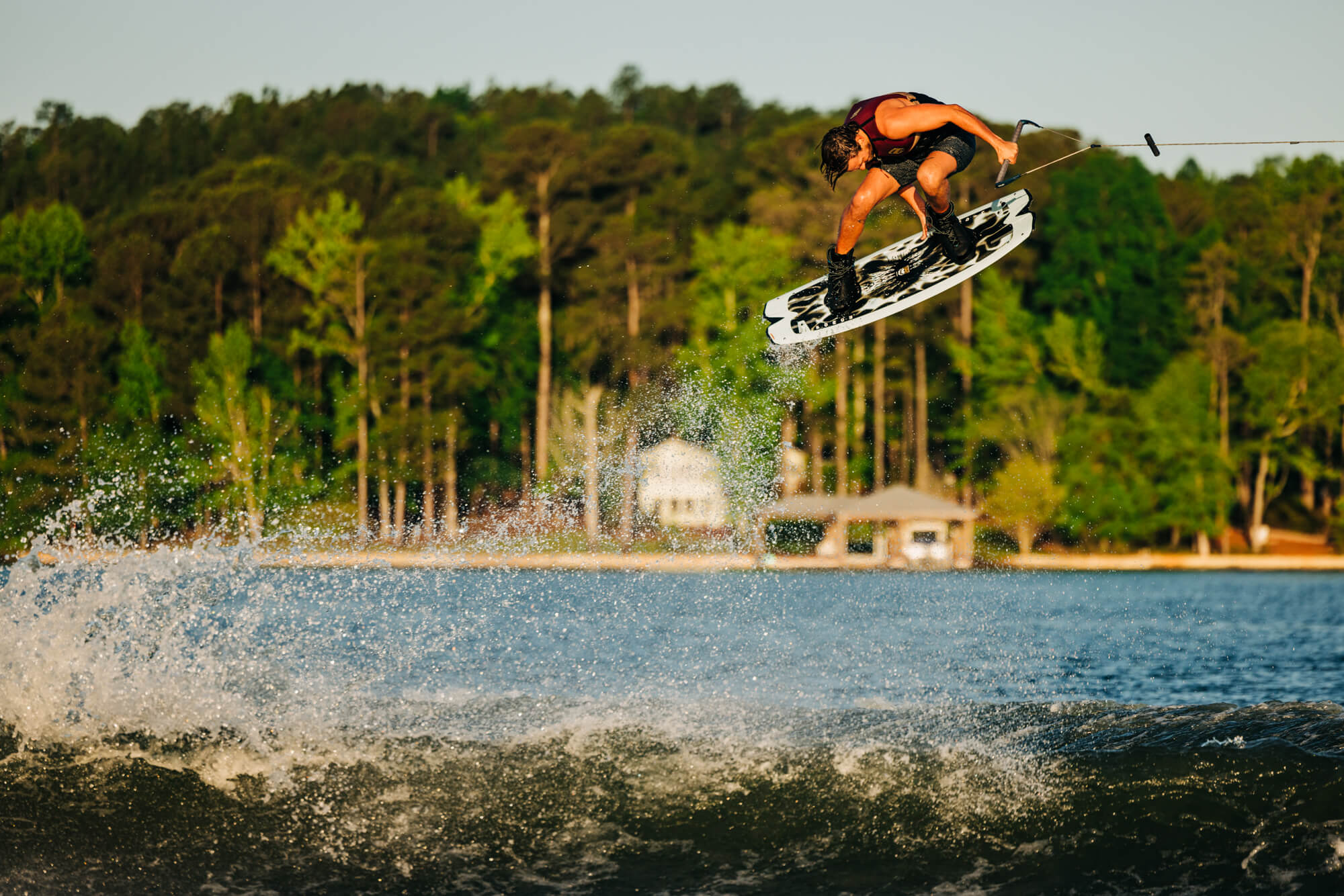 A lightweight man showcases his Liquid Force 2024 Remedy Aero Wakeboard (Pre-Order) skills in the water.