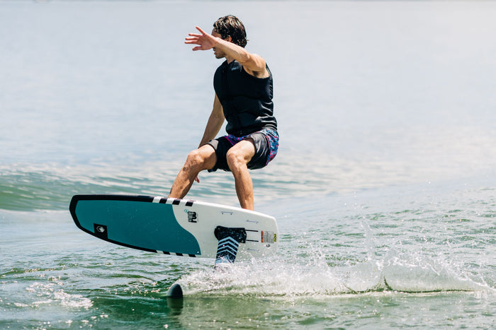 A man is wakesurfing on a Liquid Force 2024 Pod | Flite 120 Foil Package in the water.