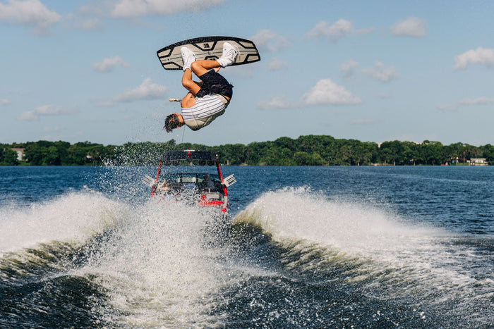 A man showcasing his lightweight performance and dexterity on a Liquid Force 2023 Unity Aero Wakeboard with CNC'd Liquid Force AERO core bindings.