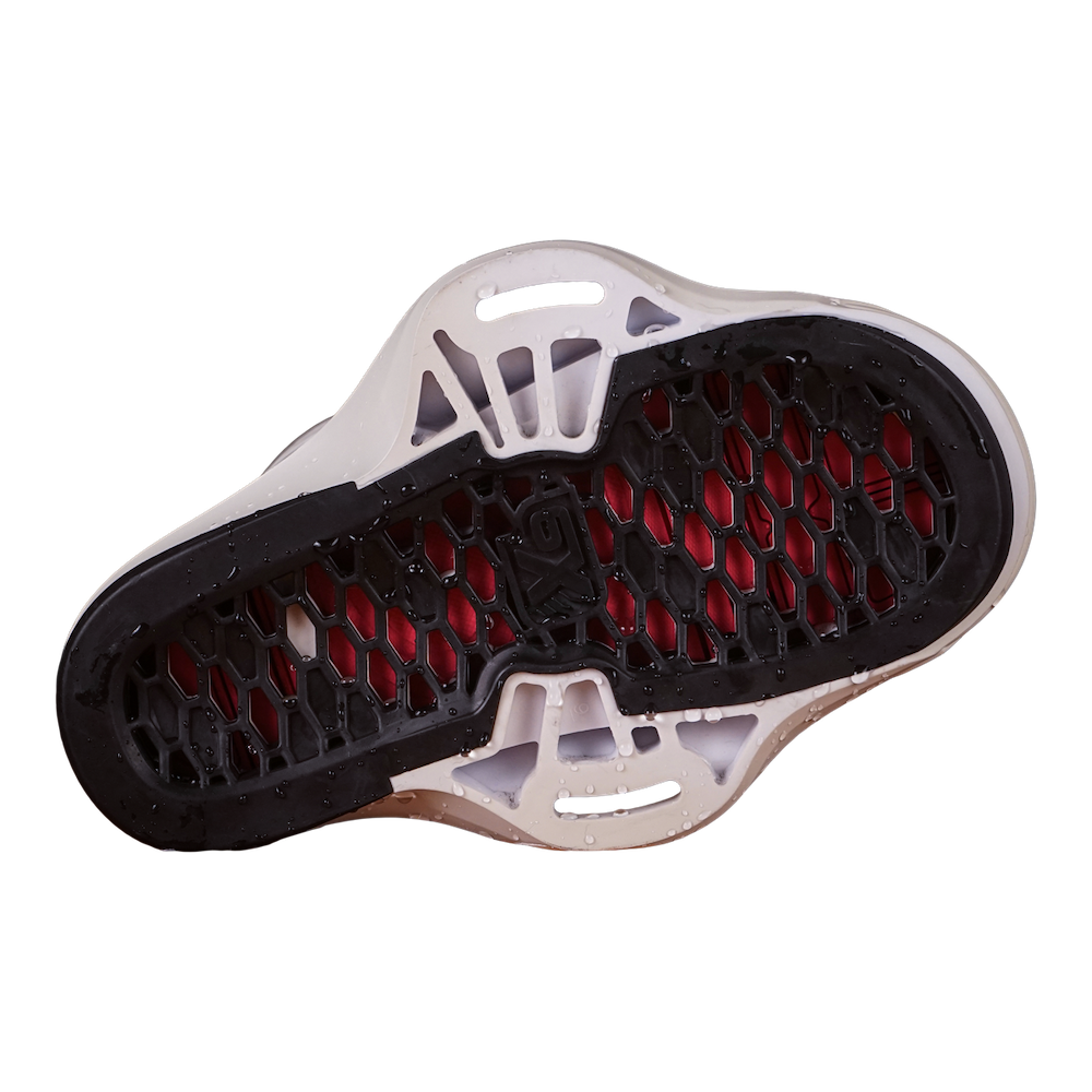 The image showcases the sole of the Liquid Force 2025 Aero 6X Boots, featuring a black tread, red accents, and a honeycomb pattern reminiscent of premium wakeboarding footwear.