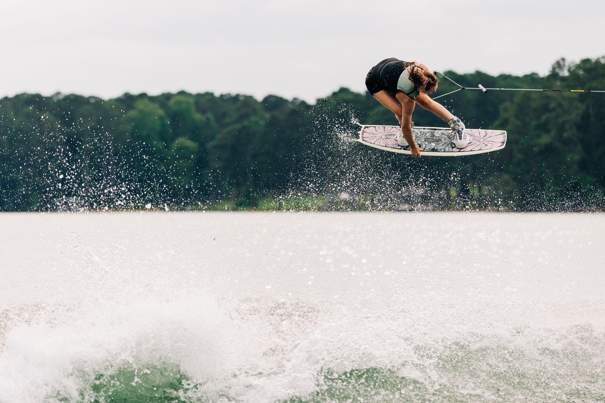 Liquid Force 2025 M.E. Wakeboard Action Shot Meagan Ethell Grabs Indy while she pokes out her new 2025 wakeboard