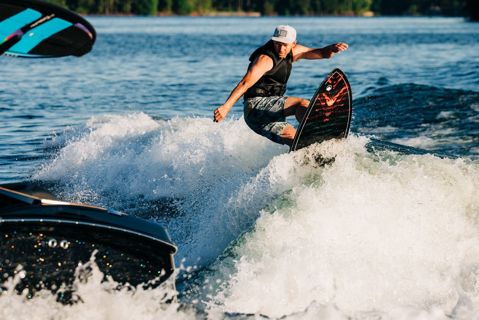 A person glides behind a boat on the Liquid Force 2025 Syncro Wakesurf Board, demonstrating exceptional stability and finesse with its skim profile on a sunny day, surrounded by water and waves.