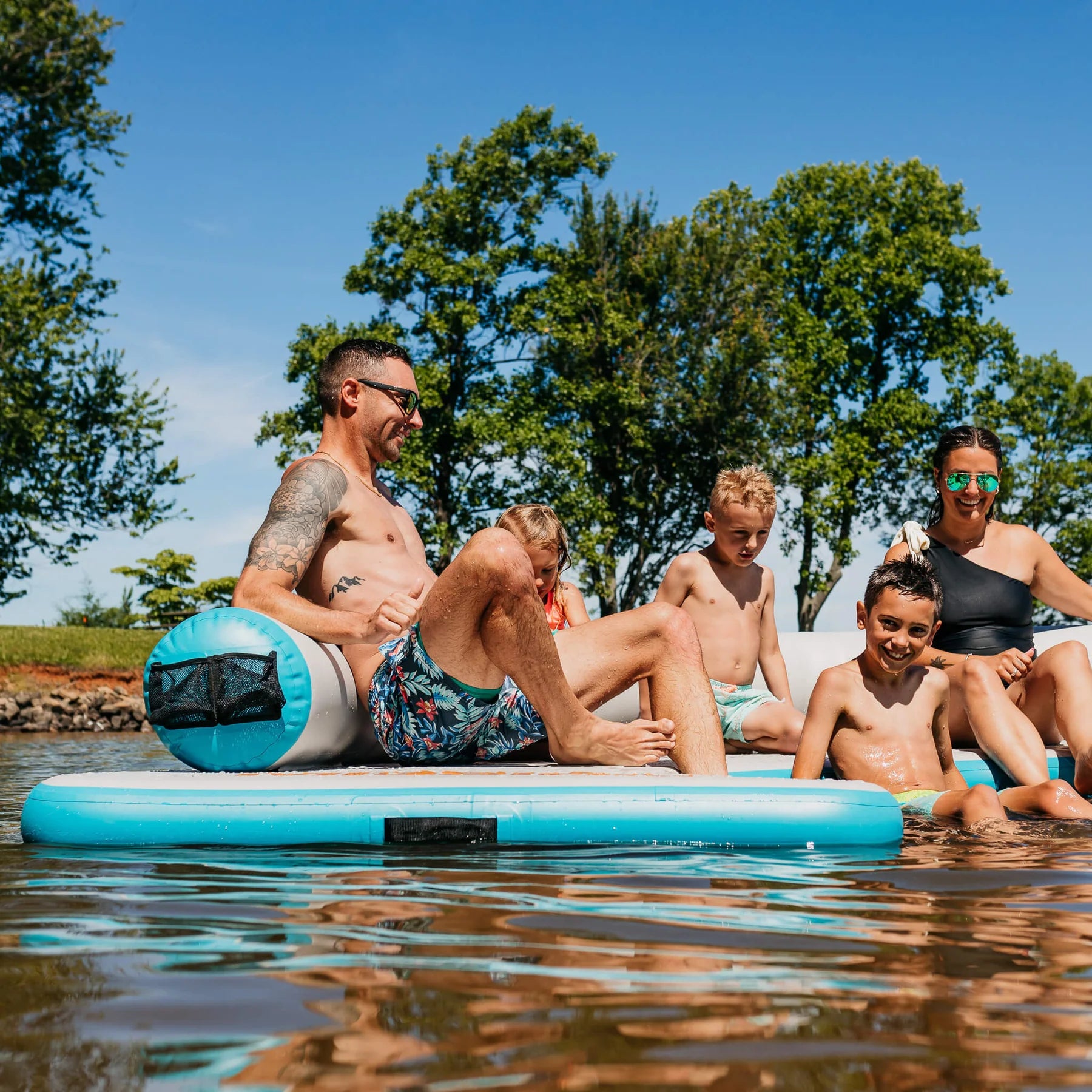 Family relaxes under the sun on the MISSION Reef Lite Lounge Inflatable Water Mat (6.5' x11.5' x 6')