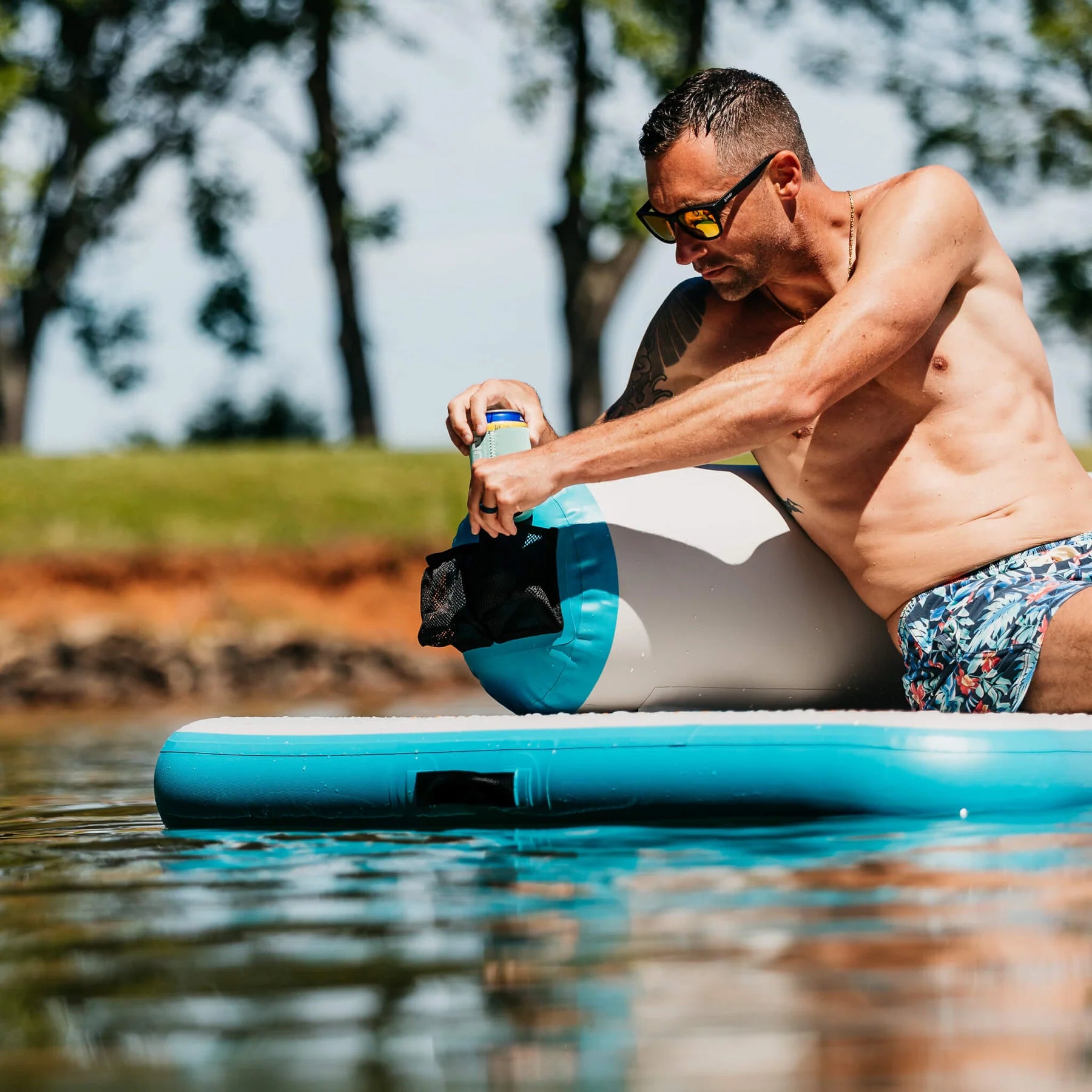 Gentleman puts his drink away in the easy access cup holder on the MISSION Reef Lite Lounge Inflatable Water Mat (6.5' x11.5' x 6')