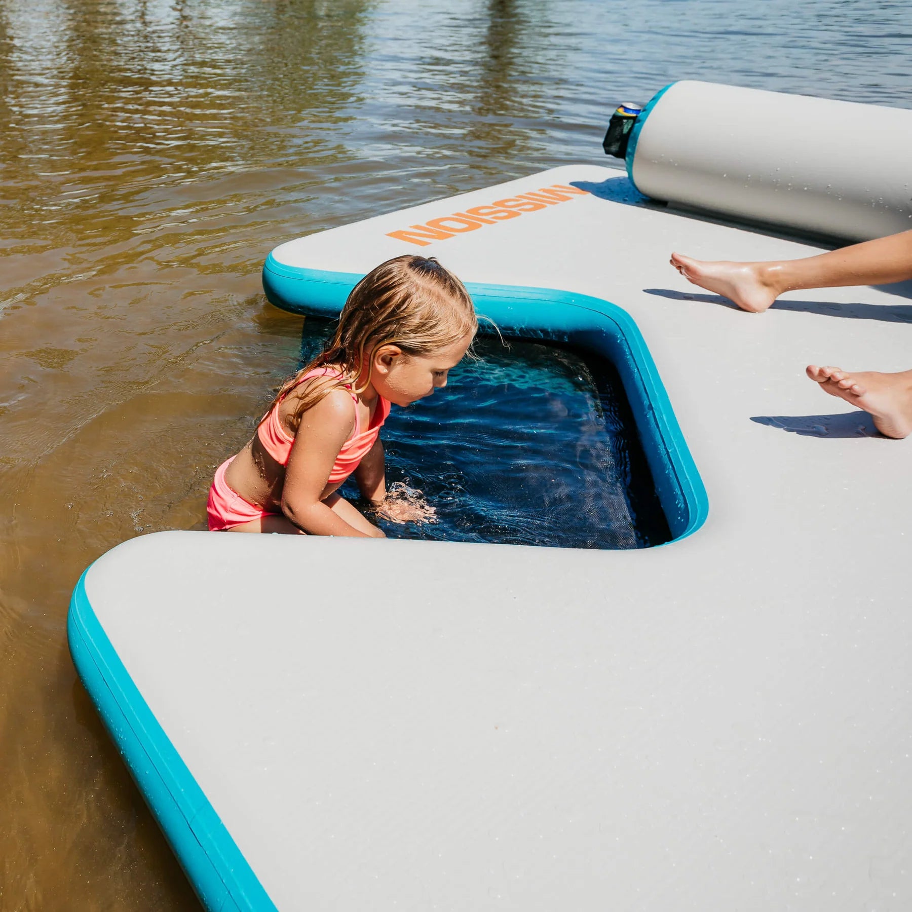 Little girl climbs onto the MISSION Reef Lite Lounge Inflatable Water Mat (6.5' x11.5' x 6') after playing in the water