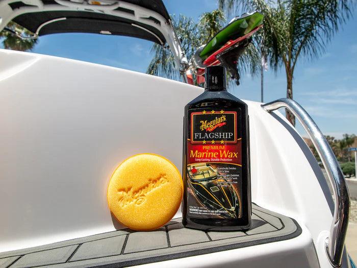 Meguiar's Flagship Marine Wax bottle with a yellow sponge on a boat deck.