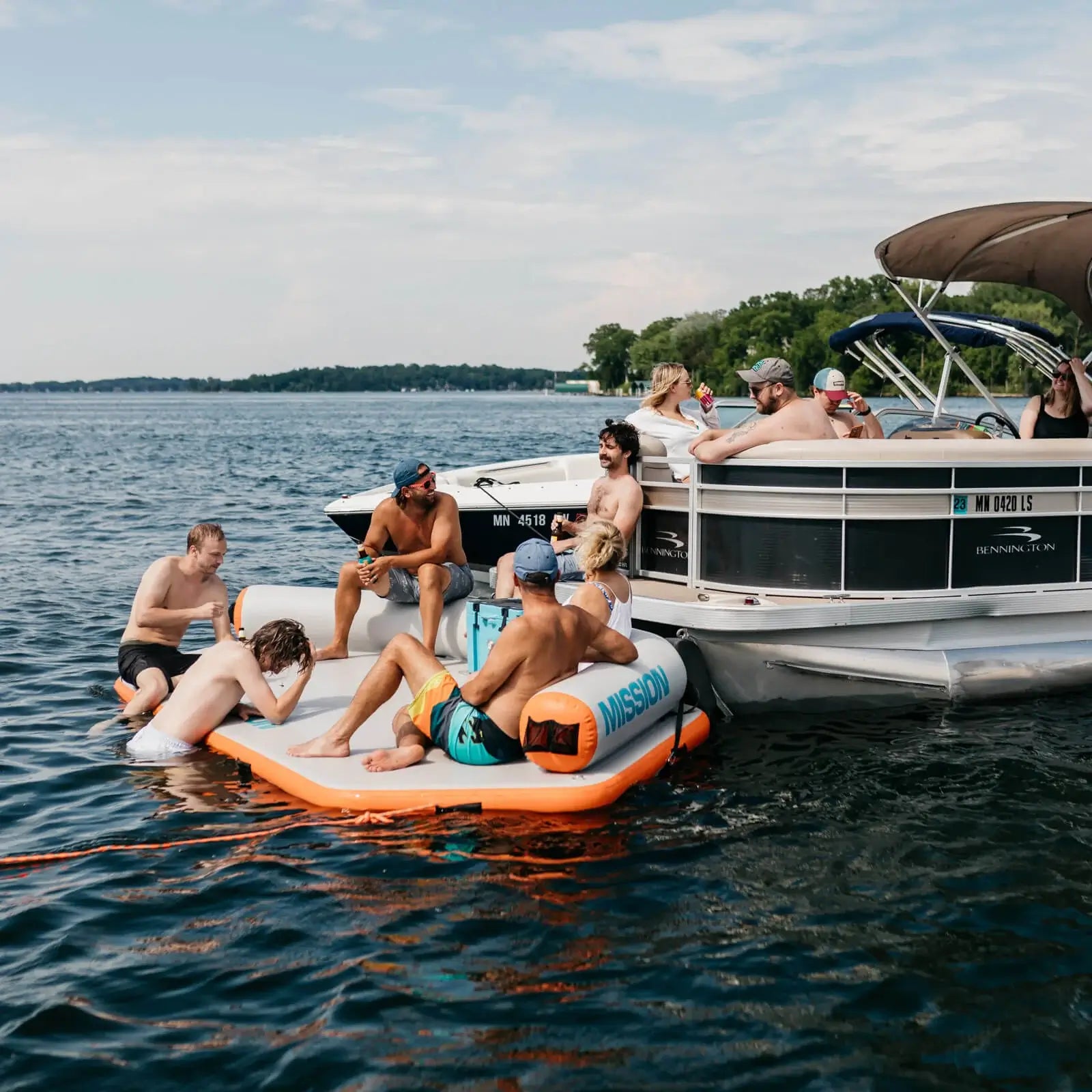 A group of people enjoying their time on a MISSION Reef Deck Inflatable Swim Platform + Lounger on a lake.