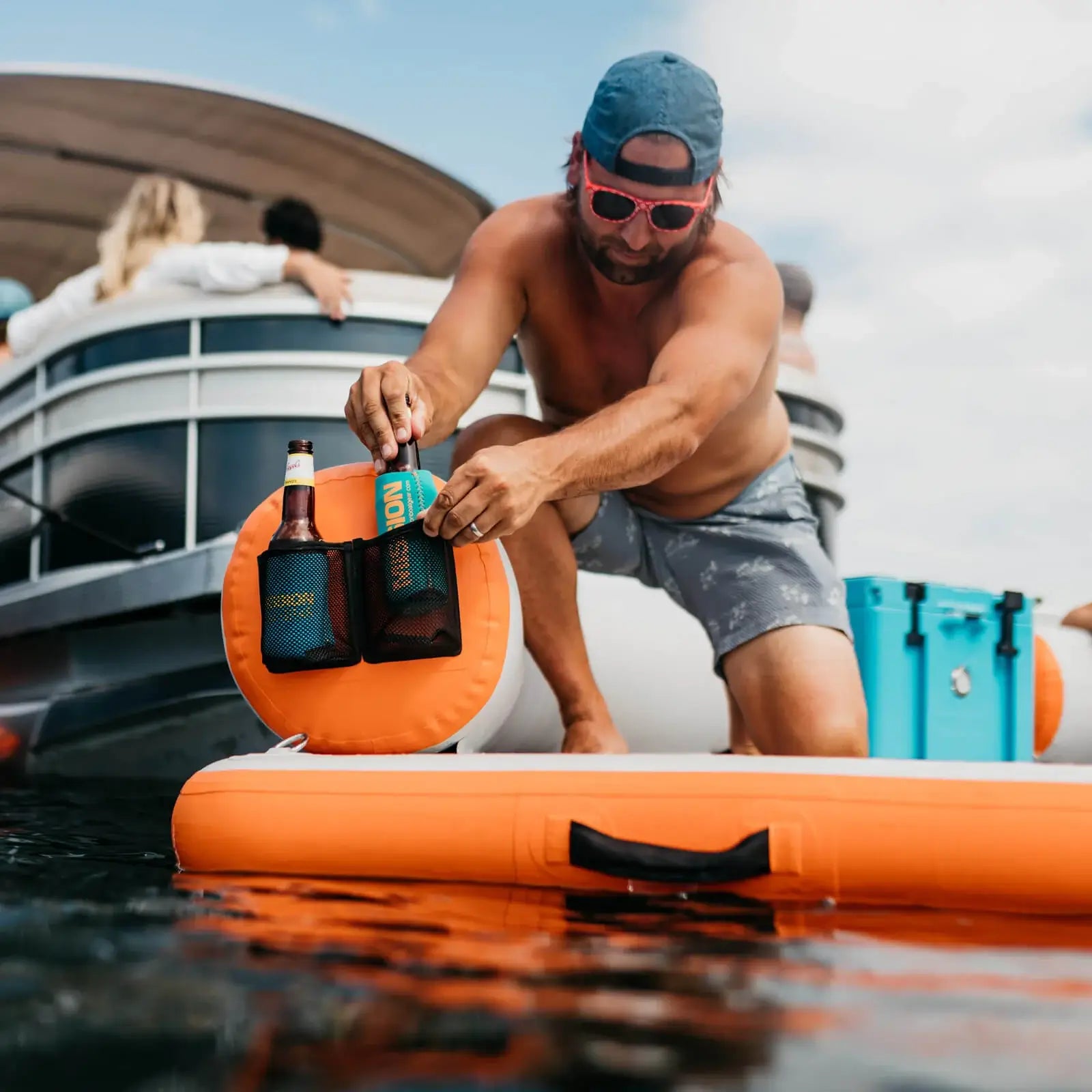 A man on a boat with MISSION Reef Deck | Inflatable Swim Platform + Lounger accessories in his hands.