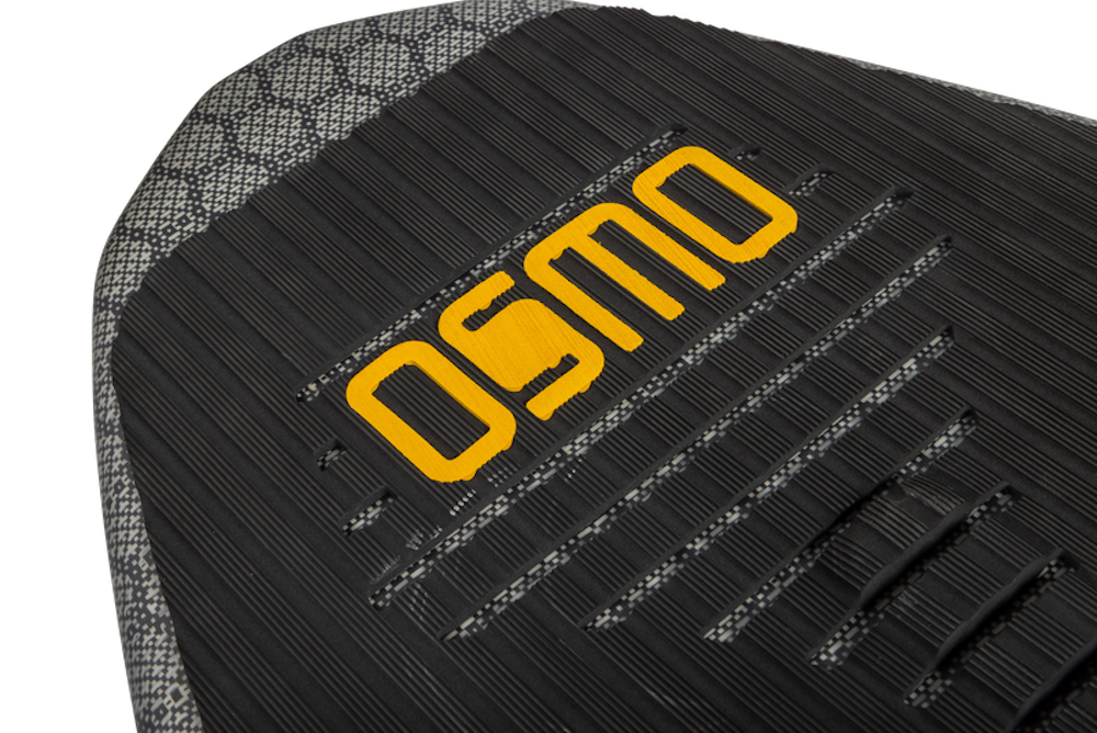 Close-up of a textured surface highlighting the word OSMO in yellow, set against a backdrop of black horizontal lines, reminiscent of the twin-tip design on the Ronix 2025 H.O.M.E. Carbon Pro Osmo Wakesurf Board, embodying the precision required for technical skim tricks.