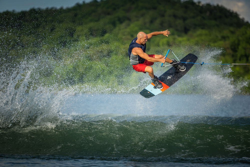 A man is wakeboarding on the water, using the Hyperlite 2024 Murray Pro Wakeboard with the Biolite 3 Core and enjoying the Subtle 3-Stage Rocker experience.