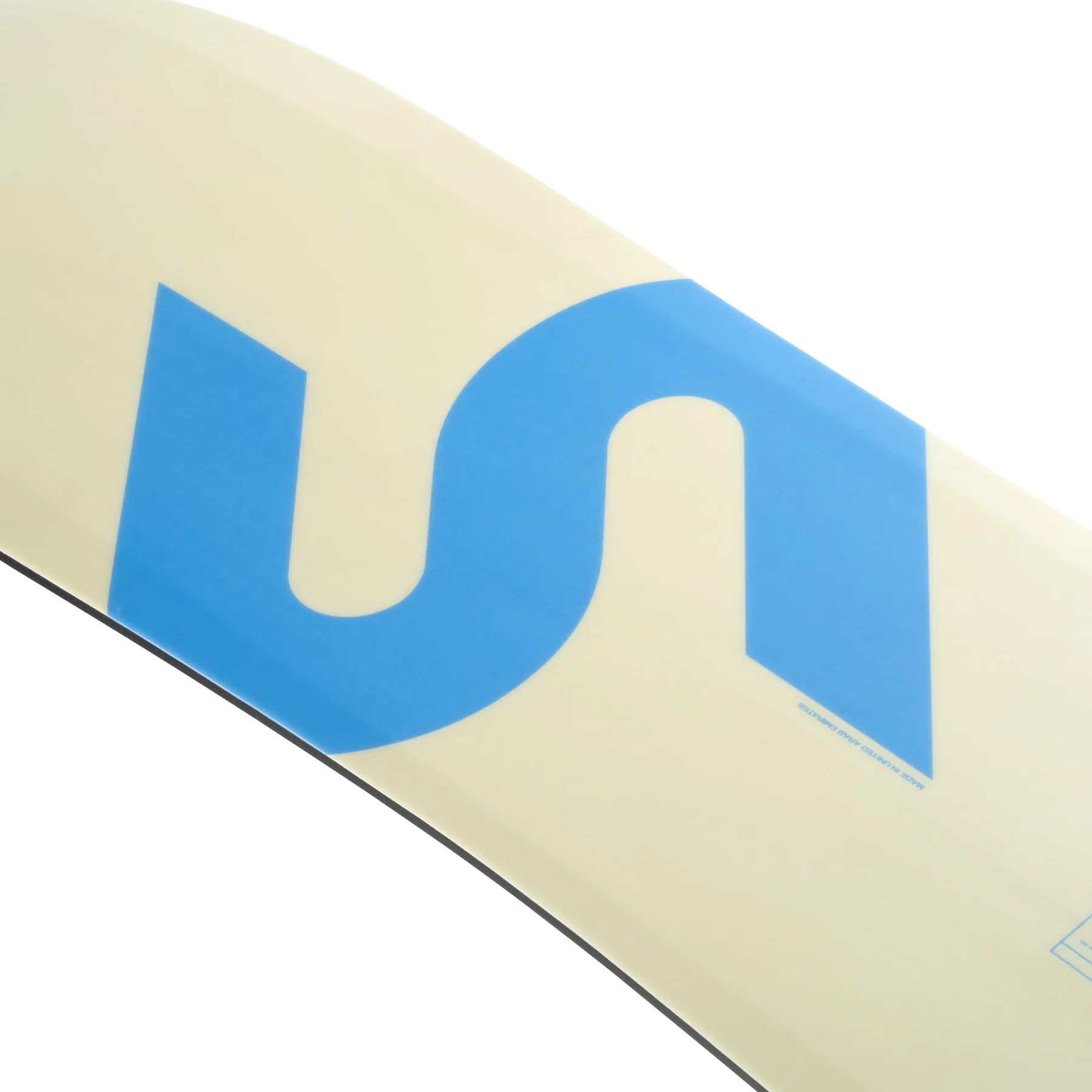 Close-up of the Slingshot 2025 Space Rover Wakeboard, showcasing a light yellow background with a large blue stylized letter S and constructed with an Atomic Wood Core.