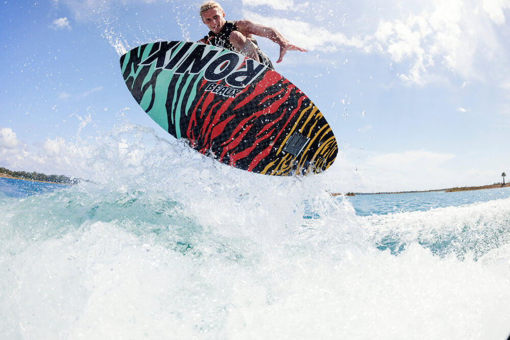 A man is riding a Ronix 2024 Beaux Skimmer Wakesurf Board in the water.
