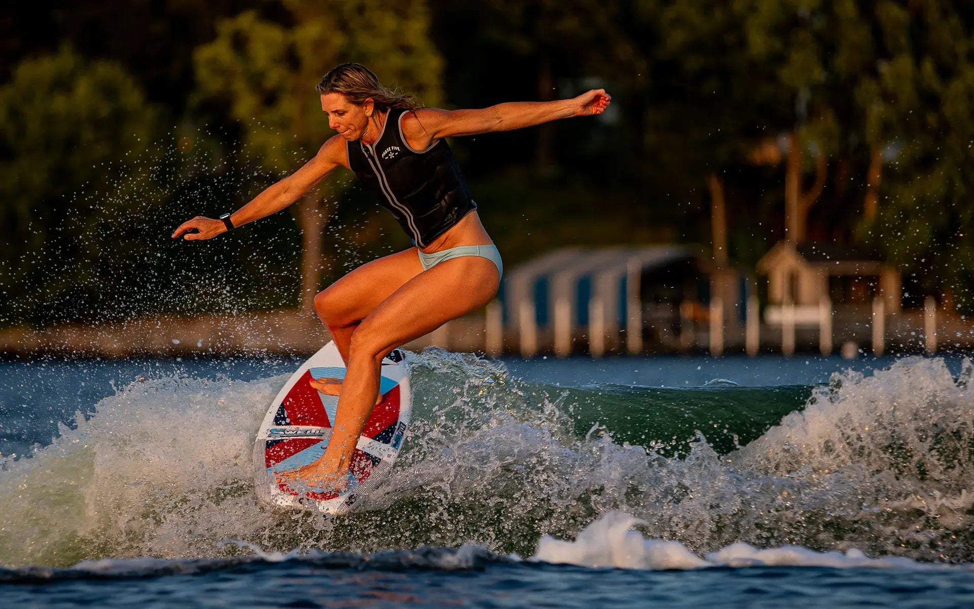 Stacia Bank, a high performance surfer, skillfully rides a wave on a surfboard, showcasing her expertise on the Phase 5 2024 Swell Wakesurf Board.