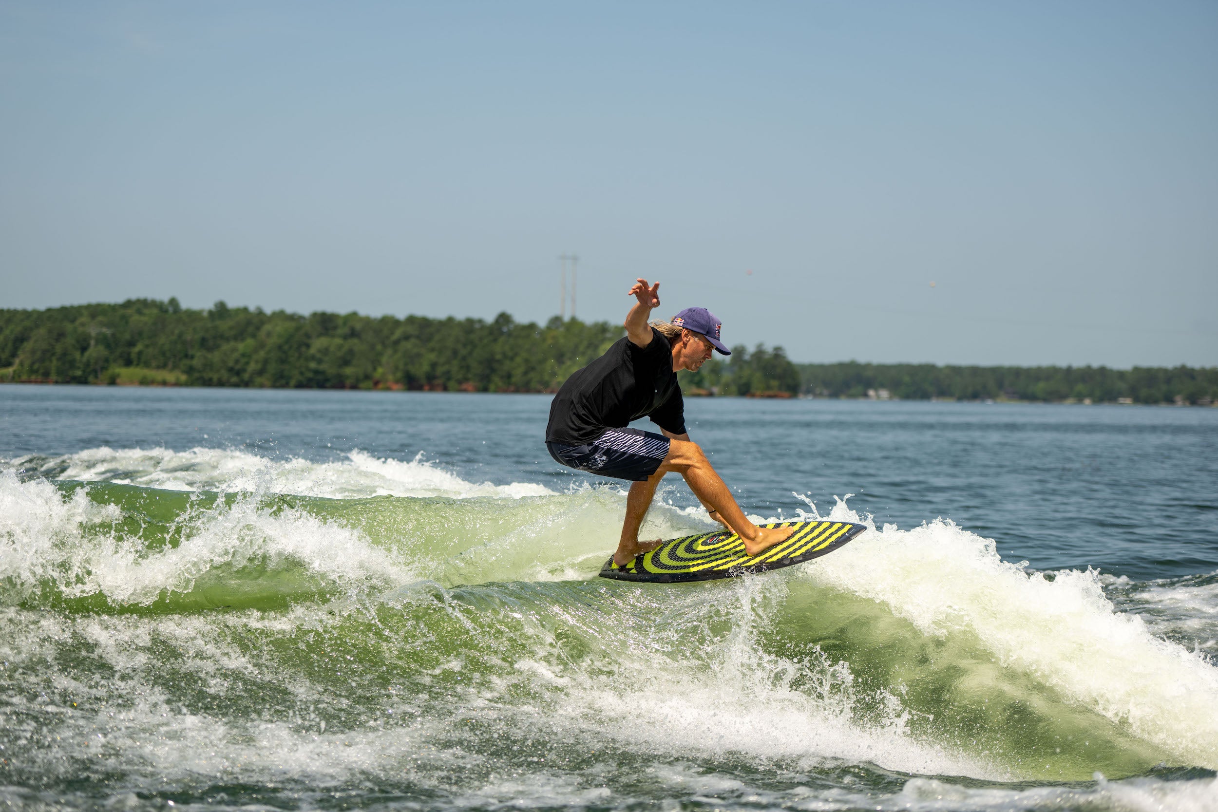 A Hyperlite wakesurf enthusiast riding a wave on a Hyperlite 2024 Shim wakesurf board.