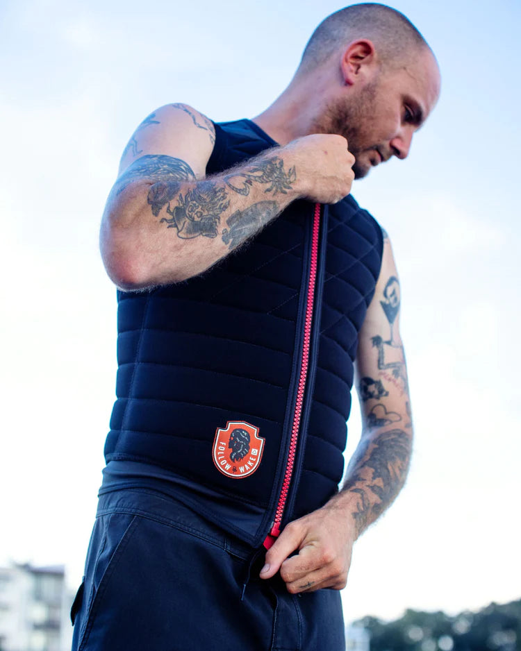 A man with tattoos is putting on a Follow Wake 2022 BP Pro Men's Jacket - Black.