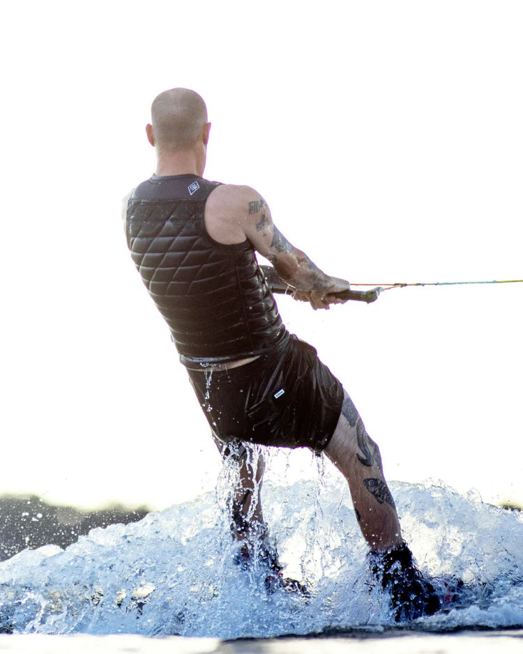 A man is water skiing in the Follow 2022 BP Pro Men's Jacket - Black by Follow Wake on a durable body of water.