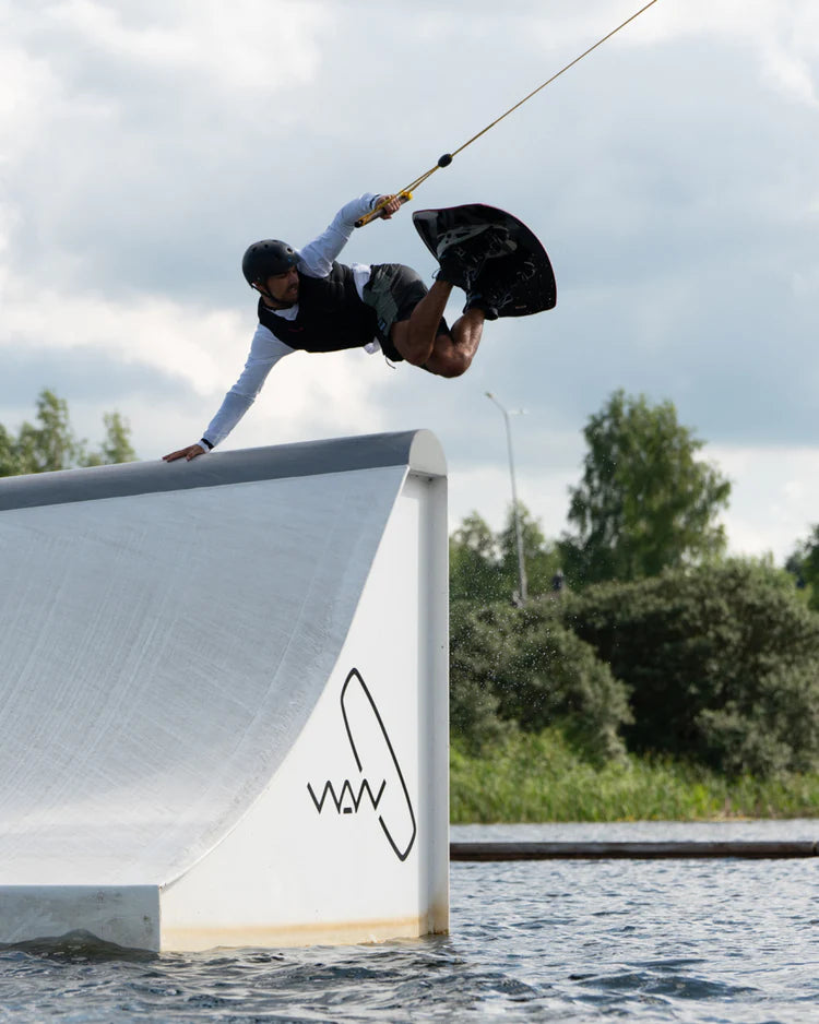 A man is performing a thrilling trick on a wakeboard while wearing a Follow 2022 TBA Men's Jacket - Black vest.