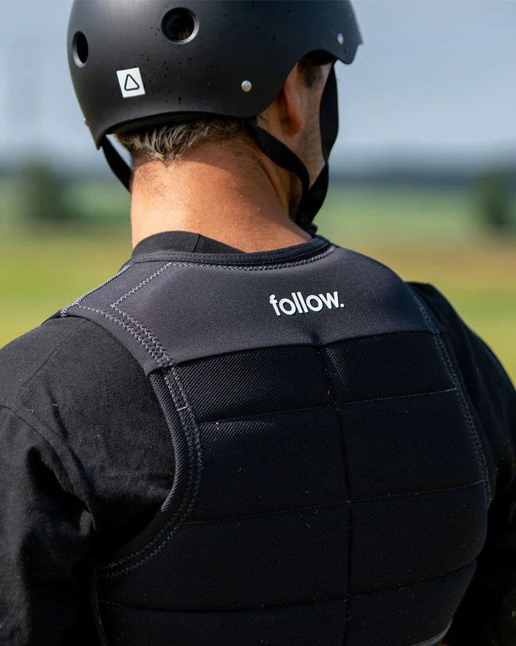 The back of a man wearing a Follow Wake helmet with the word follow on it.