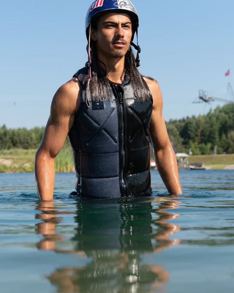 A man in a wetsuit standing in the water, showcasing the Follow Wake Unity Men's Jacket - Black with a true fit liner.