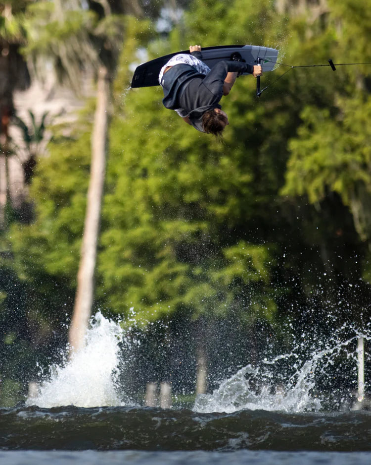 A person performing a trick on a wake board, wearing the Follow 3.12 Anorak Pro Neo Outer Jacket - Charcoal to combat the wind chill factor and utilizing Aquaguard® Stash pockets. (Brand: Follow Wake)
