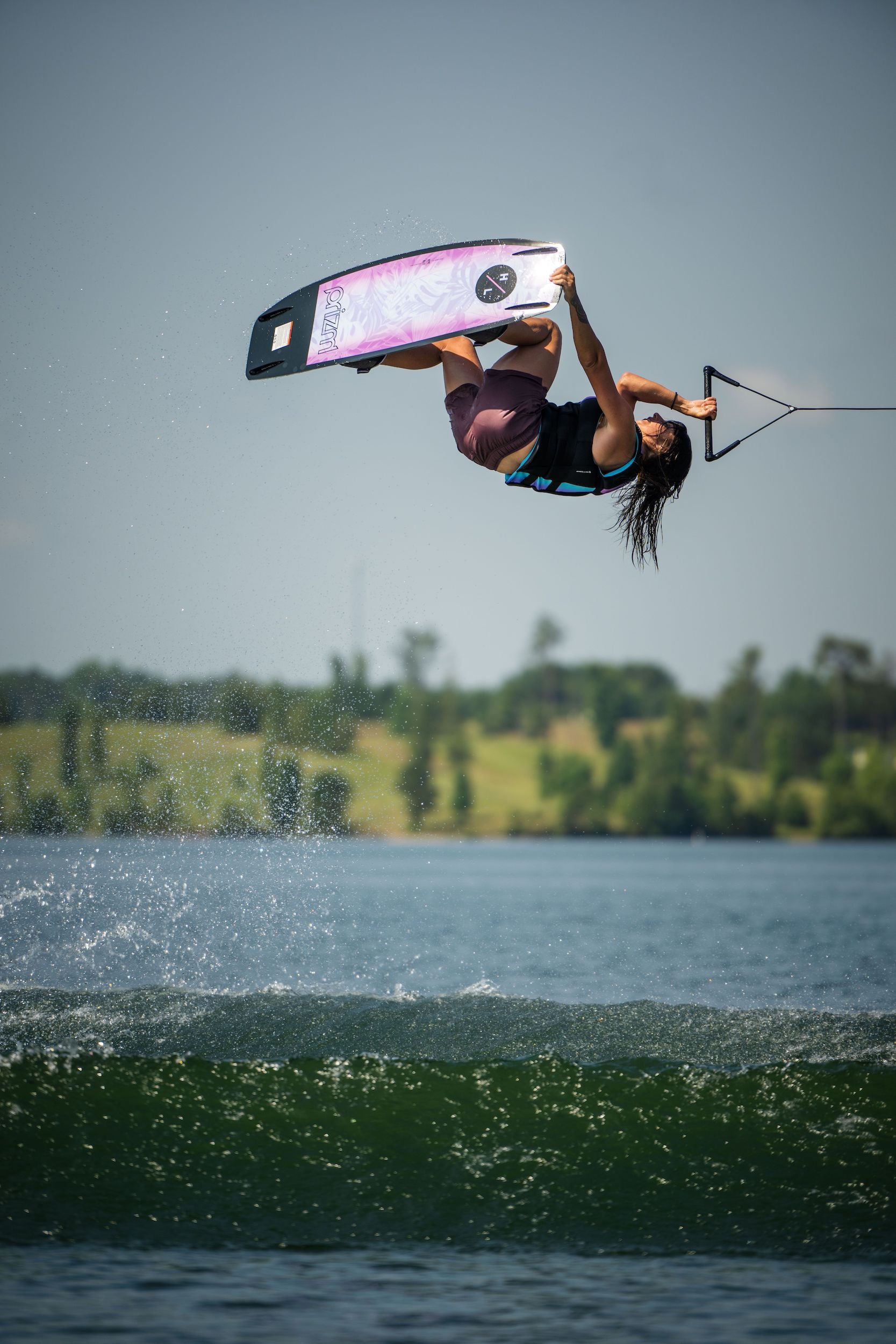 A Hyperlite 2023 Prizm Wakeboard inspired woman gracefully defies gravity while wakeboarding.