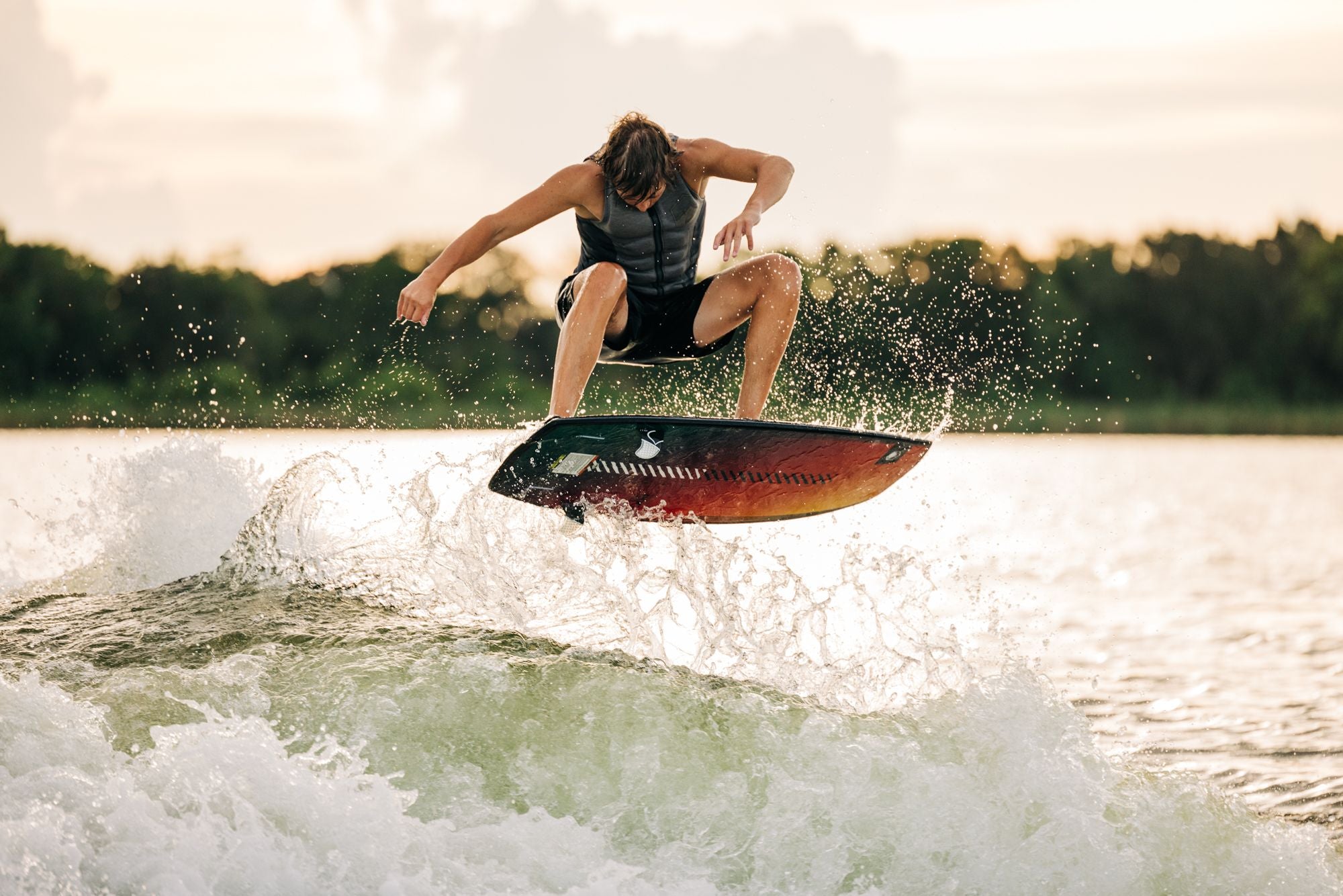 A man is riding a Liquid Force 2024 Pod Wakesurf Board on a lake.