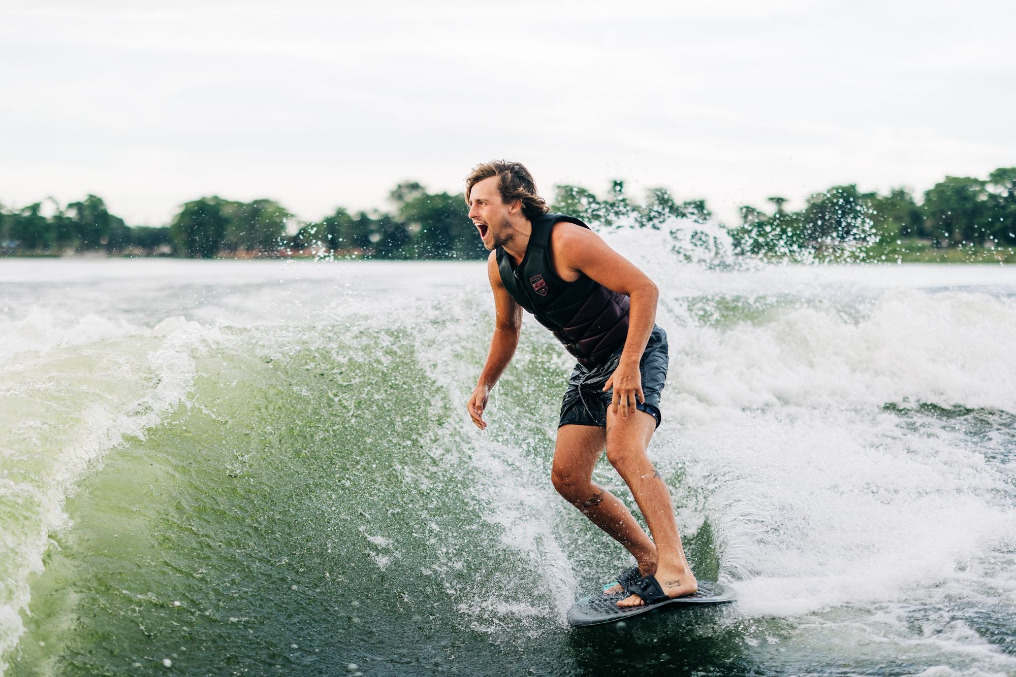 A man riding a wave on a surfboard equipped with durable foot straps, ensuring a secure Liquid Force 2023 Primo ride on the Dura-Surf.