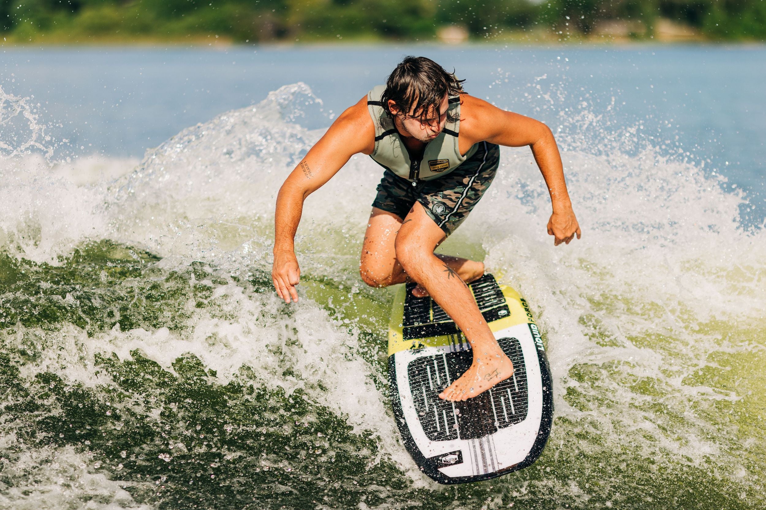 A man showcasing his impeccable maneuverability on a Liquid Force 2023 Space Pod Wakesurf Board, effortlessly displaying exceptional performance while riding a wave.