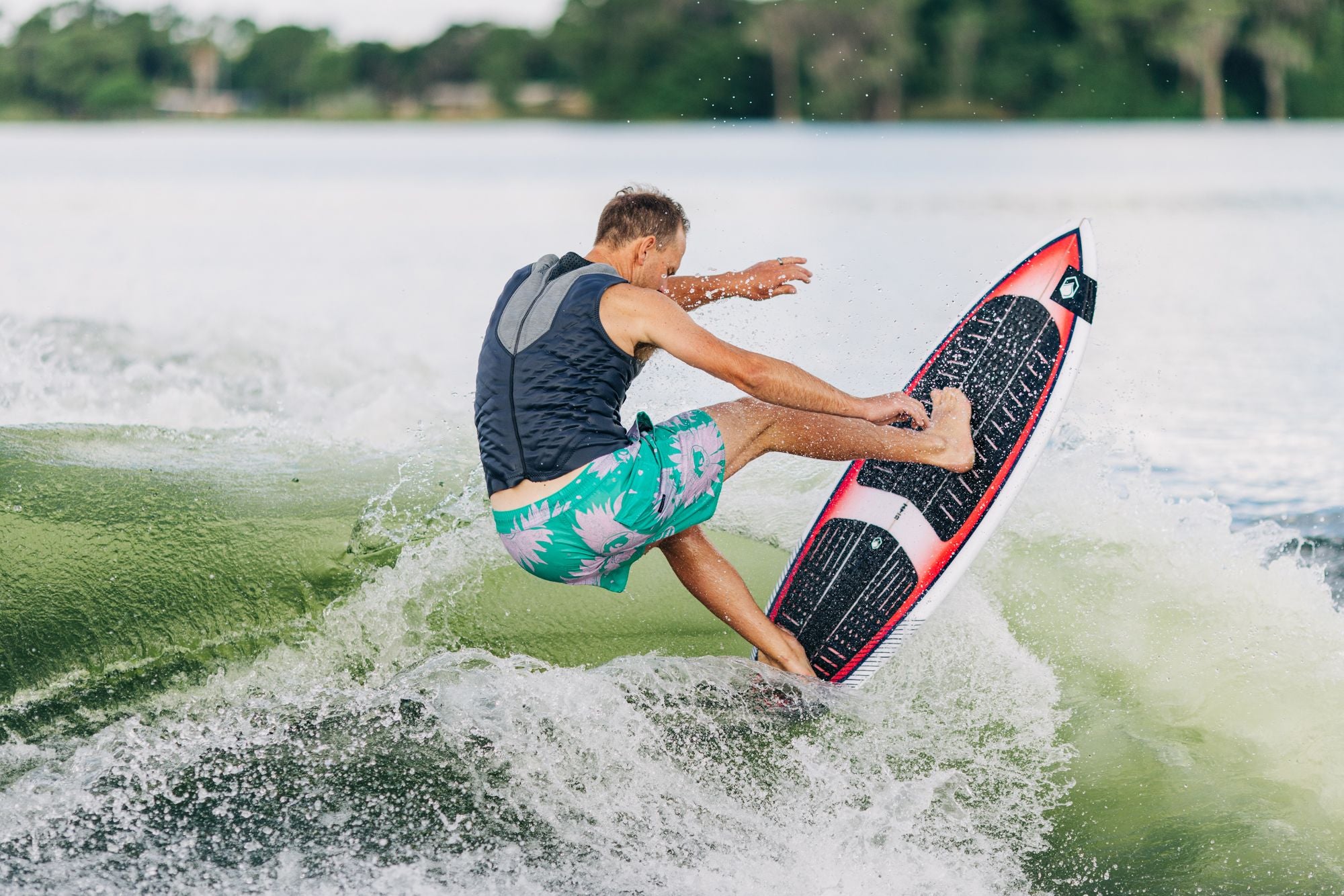 A man wakesurfing on a lake using a lightweight Liquid Force 2024 TC Skim Board.