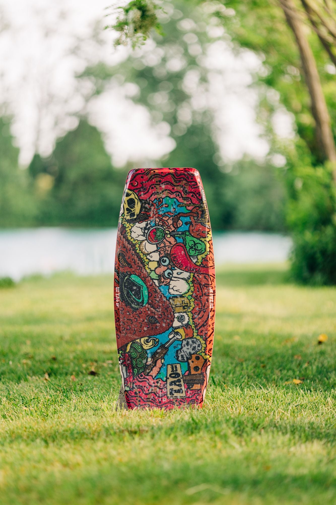 A Liquid Force 2023 Tao Wakeskate in the grass next to a lake.